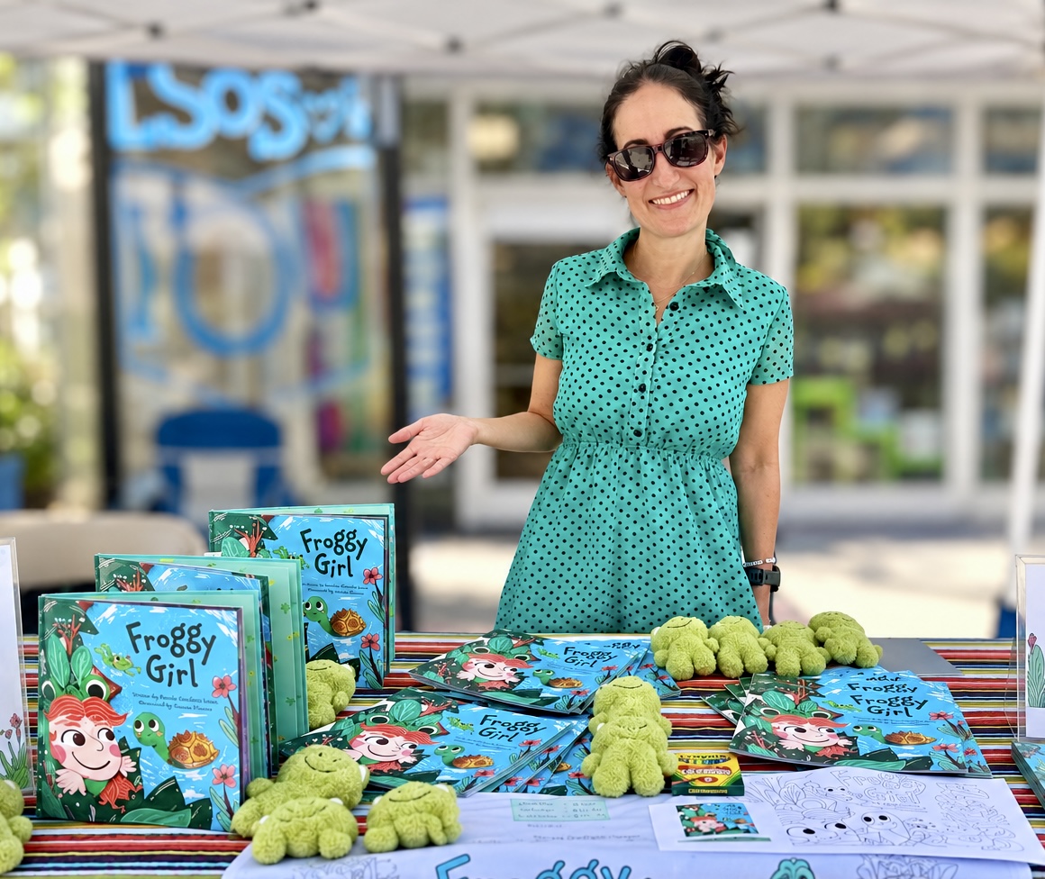Pamela Garfield-Jaeger at a book fair signing table with copies of Froggy Girl and plush frogs